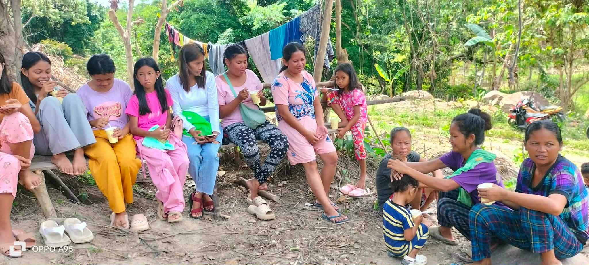 Women and children seated together during an outdoor community gathering